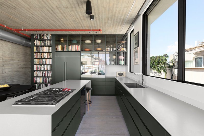 Galley kitchen with dark green cabinetry and white countertops beneath board-formed concrete ceiling and exposed ductwork