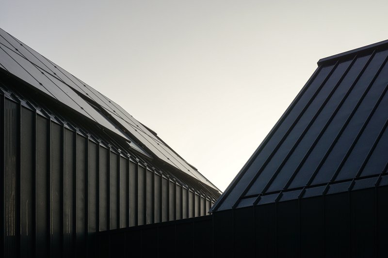 Upward view of two gabled rooflines meeting in a V against an overcast sky
