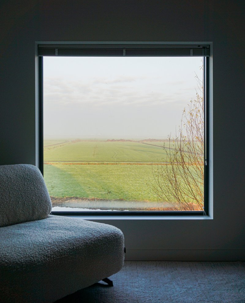 Square window seat overlooking green farmland and grasses in misty weather
