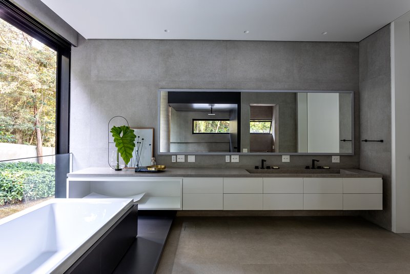 Bathroom with floating white vanity beneath concrete panel walls and a planted courtyard beyond