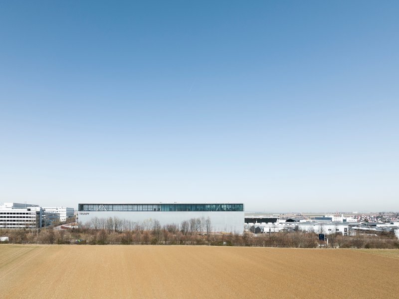 Distant view of the elevated transparent volume above industrial roofscape and bare winter trees