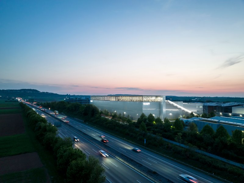 Long exposure view of the illuminated facility beside the highway with passing traffic