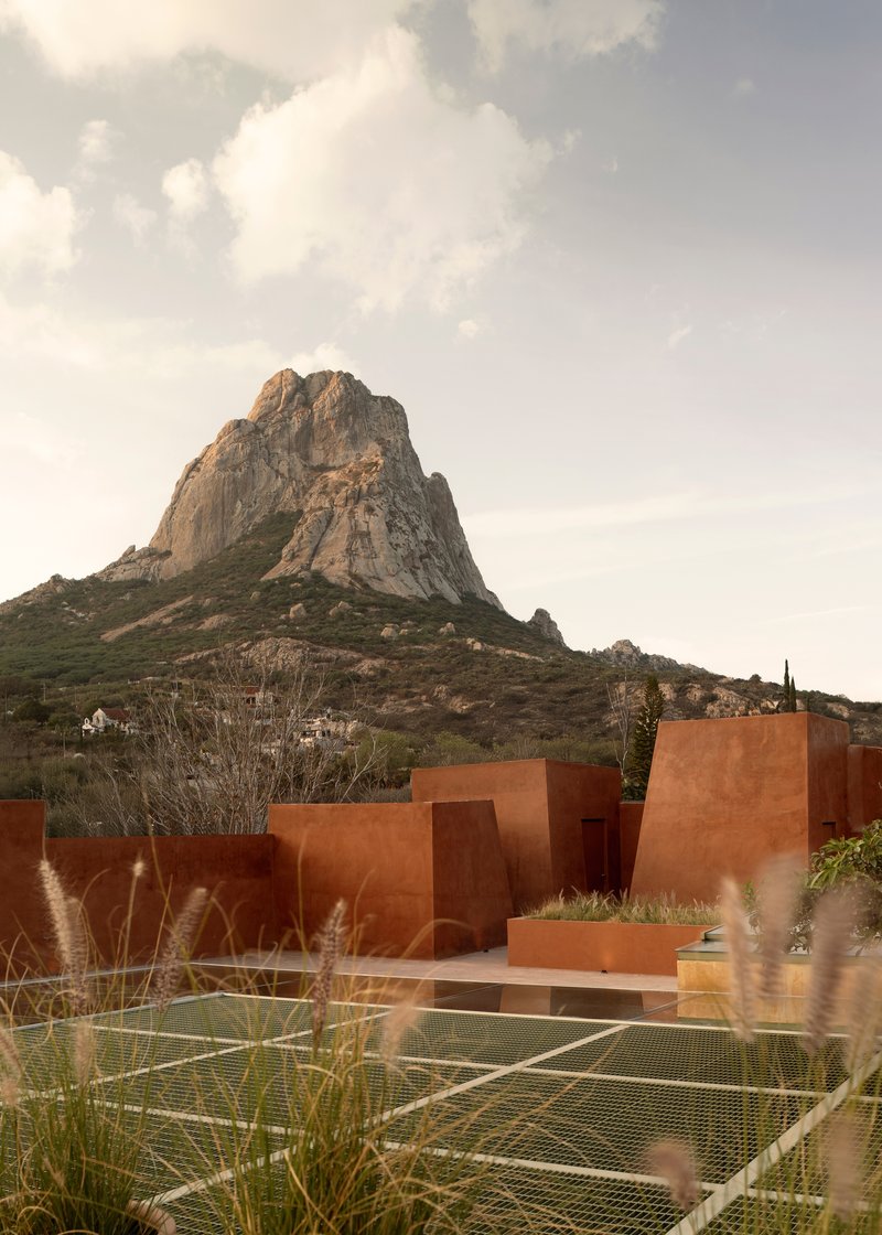 Red stucco volumes with tennis court and rocky mountain peak in the background