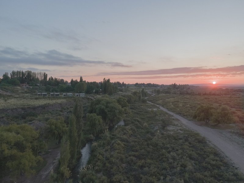 Wide landscape view showing irrigation canal bordered by poplars and scrubland at sunset