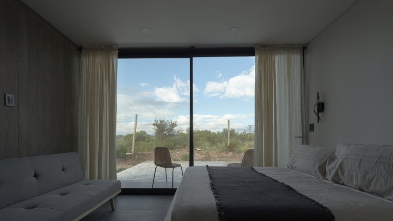 Bedroom window framing a view of desert scrubland with saguaro cacti under blue sky