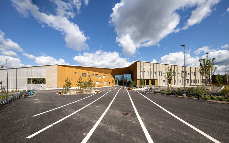 Front elevation showing the curved timber section linking two volumes under passing summer clouds