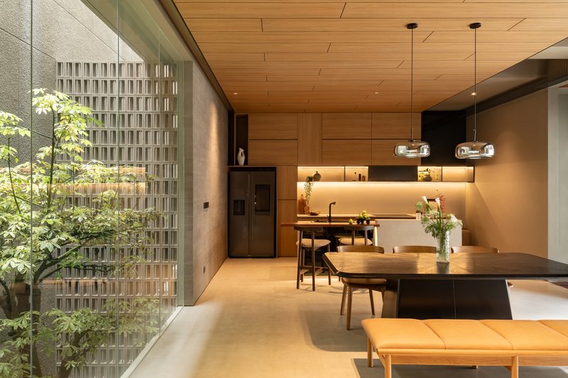 Open-plan dining and living space with timber ceiling and courtyard view through perforated screen wall