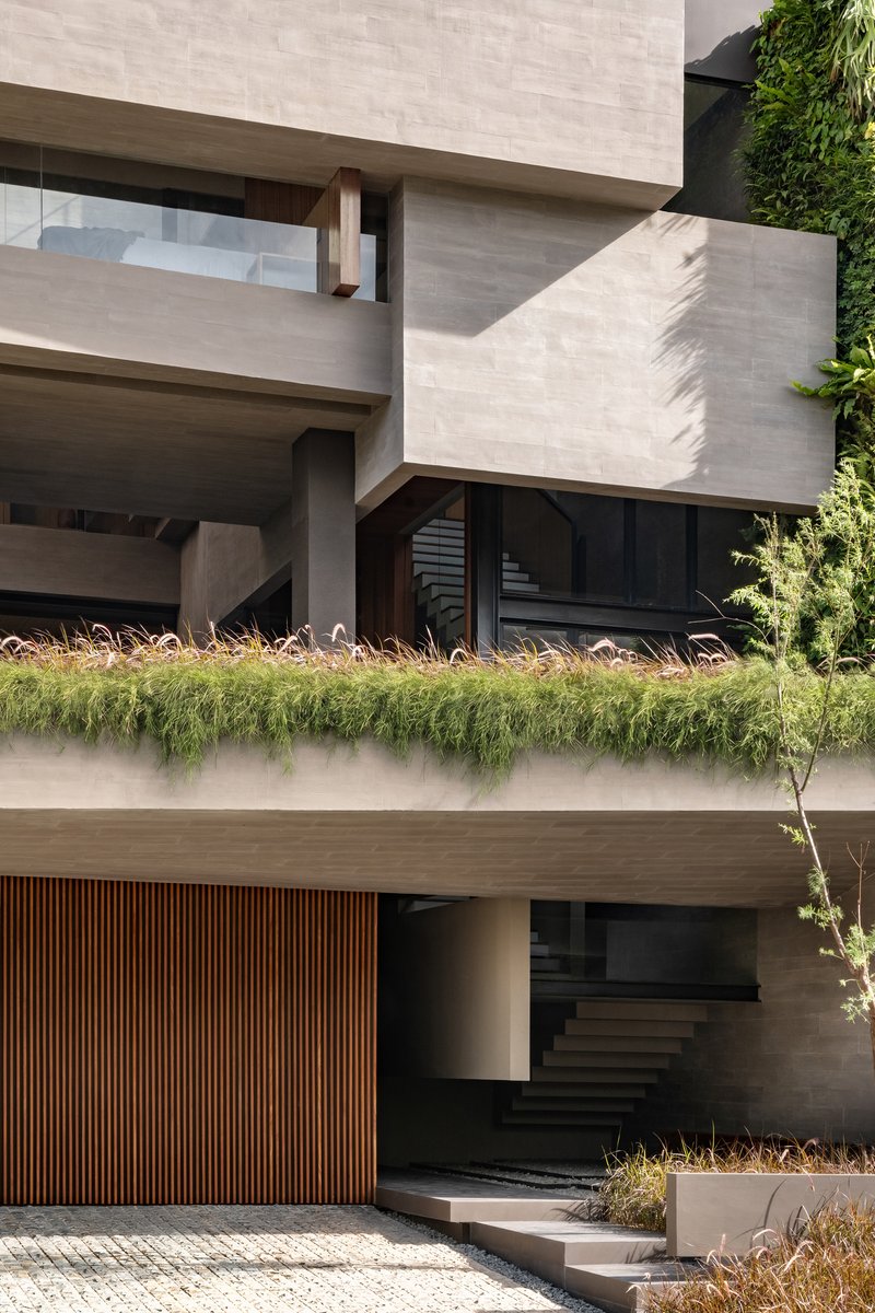 Layered concrete balconies with planted edge, timber screening and entry stair in afternoon sunlight
