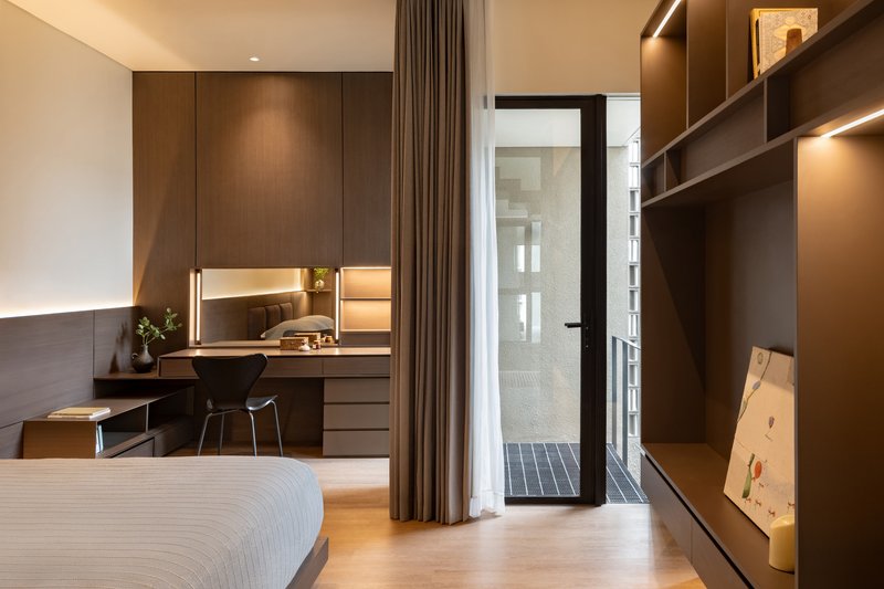 Bedroom with built-in desk and shelving facing a narrow lightwell clad in grey tile