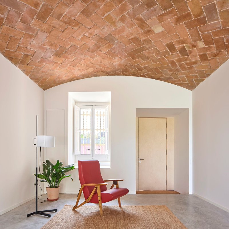 Herringbone brick vaulted ceiling over a room with arched doorways and a tall window niche