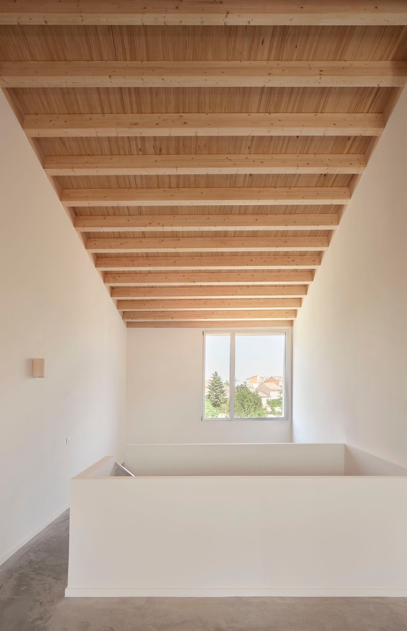 Upper level room with exposed timber joists and decking ceiling, a corner window and white volume below