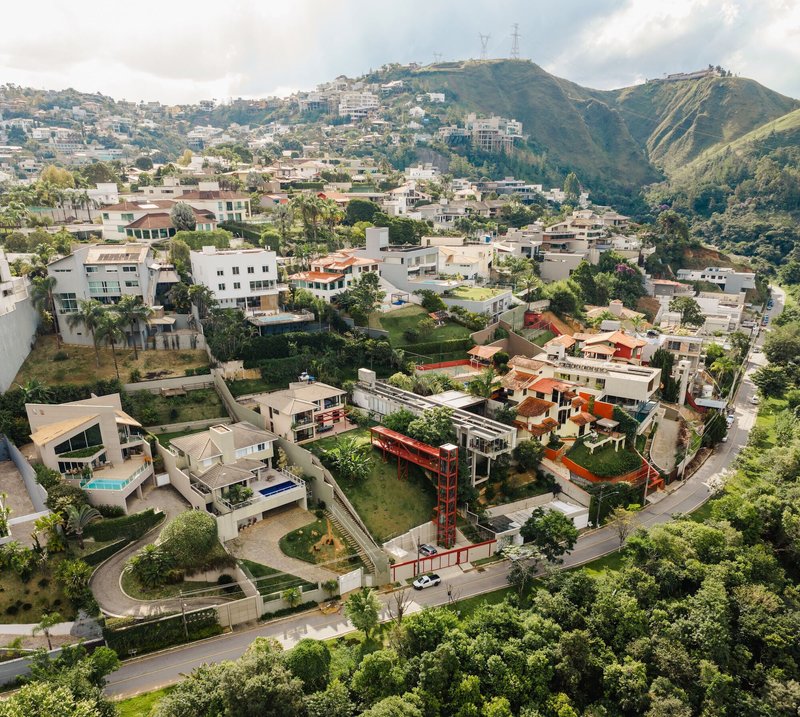 Aerial view of the residence with red steel tower on a sloping hillside neighborhood