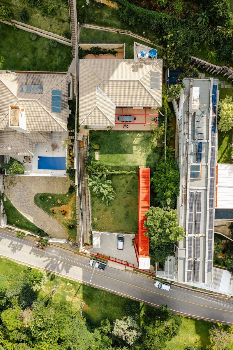 Aerial view of a narrow lot with a vertical red steel tower connecting the house to the street