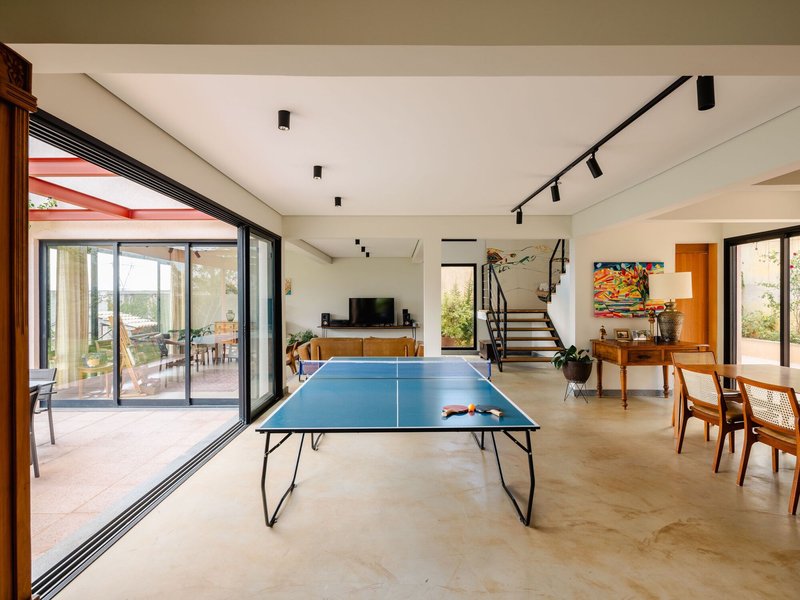 Open living space with concrete floors, ping pong table, and black-framed sliding glass doors to terrace