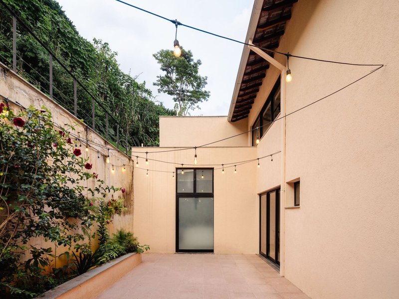Enclosed courtyard with stuccoed walls, string lights overhead, and planted bed against a retaining wall
