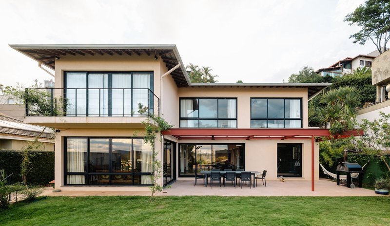 Garden facade showing two volumes with large gridded windows and a red steel frame connecting them