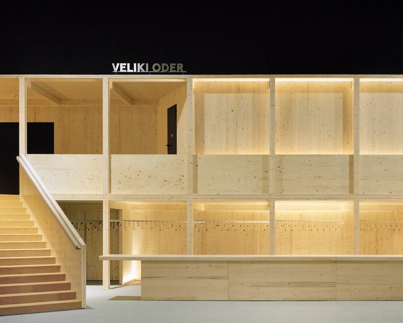 Interior view of laminated timber wall framing and staircase under warm artificial light at night