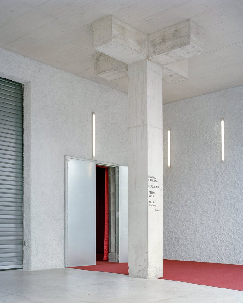 Foyer with textured white walls, vertical strip lighting, and a red carpet leading to an entrance