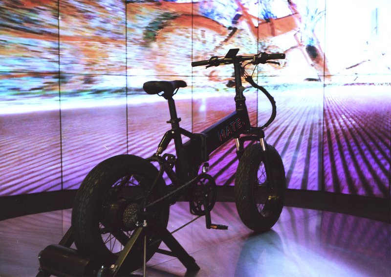Silhouetted bike on a stand against a multiscreen video wall projection
