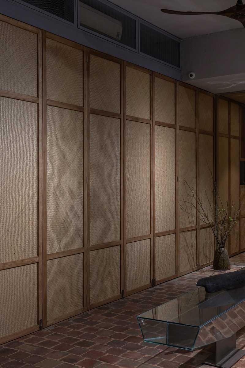 Textured rattan panel wall with timber framing adjacent to brick floor and glass coffee table