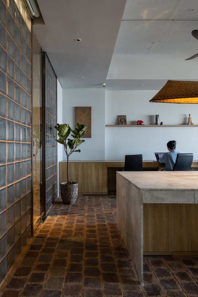Glass block partition wall flanked by reclaimed brick floor leading to timber and concrete dining table