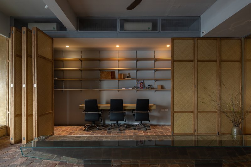 Conference room framed by folding timber screens with integrated shelving and clerestory windows above
