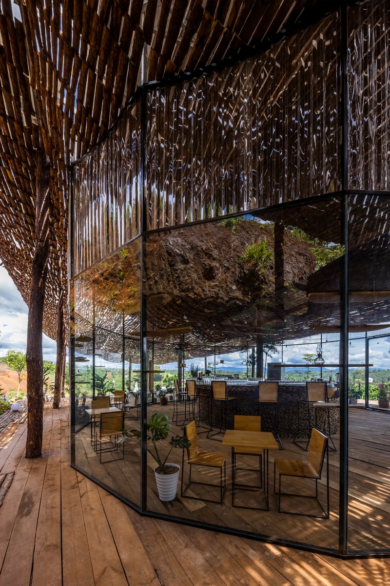 Glass-enclosed lounge area with a suspended rock feature beneath the timber lattice roof structure