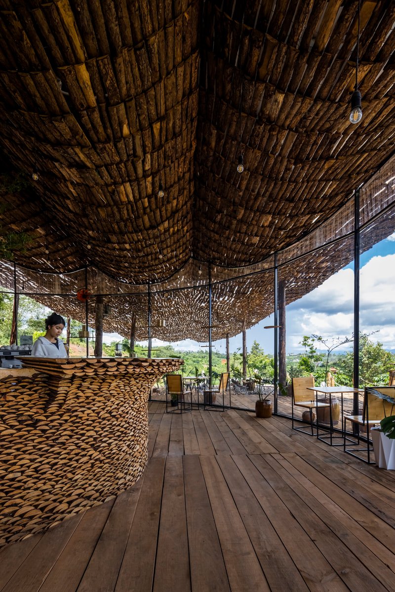 Interior view of the woven bamboo ceiling with curved timber columns and a reception counter