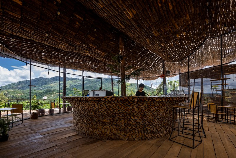 Interior bar counter wrapped in woven material under the bamboo ceiling with mountain vista through glazing