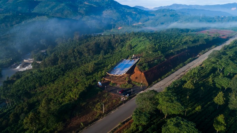Aerial view of the compound on a forested ridgeline with morning mist in the valley below