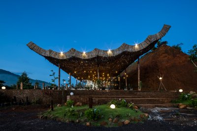 This architectural image showcases an open-air pavilion with a unique, curved wooden roof structure.