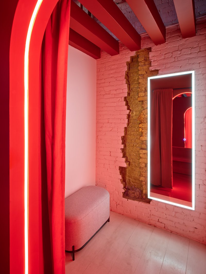 Small room with exposed brick wall, red neon-lit archway, and illuminated mirror frame