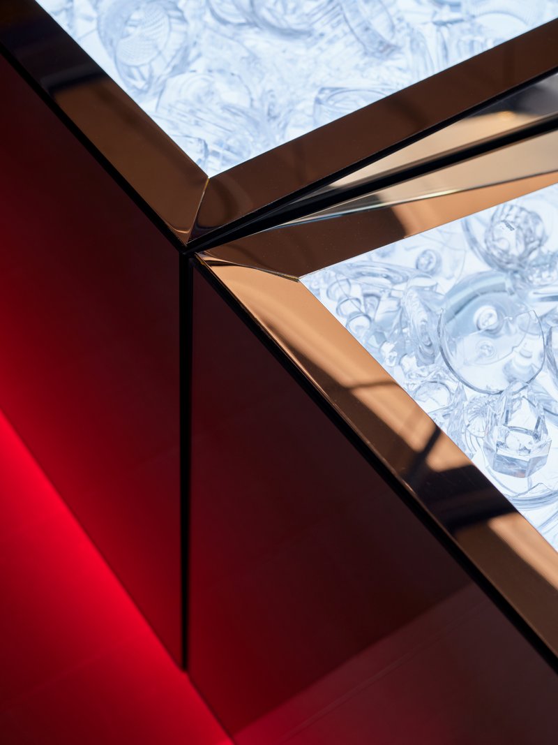 Detail of bronze metal frame corner meeting marbled blue glass panels in afternoon sun