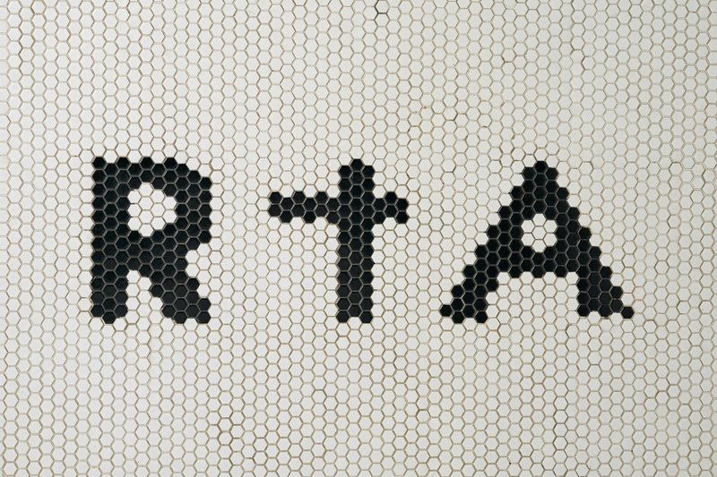 Black hexagonal mosaic tiles spelling letters on a white penny tile wall