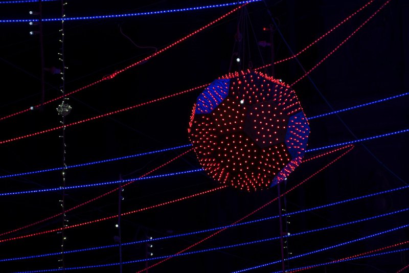 Illuminated spherical fixture with red and blue LEDs intersected by radiating horizontal light tubes at night