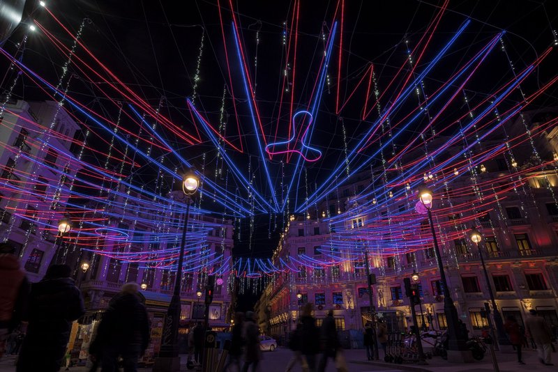 Overhead canopy of illuminated red and blue LED tubes radiating from a central point above a public square at night