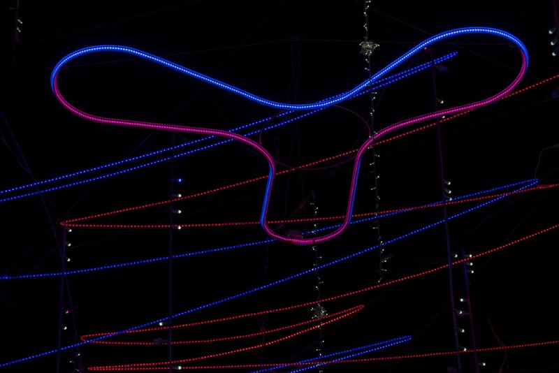 Close-up of curved LED tube forming a looping gesture against parallel red and blue linear light strands