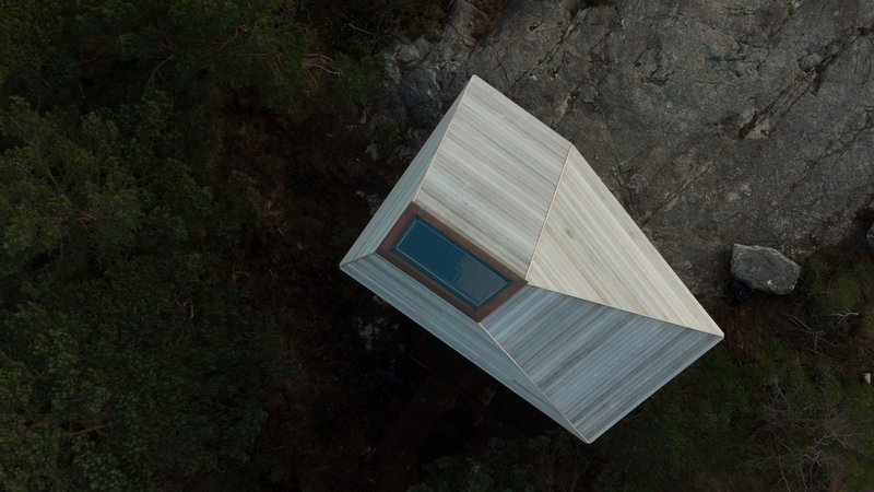 Aerial view of the gabled roof with central skylight perched on rocky outcrop