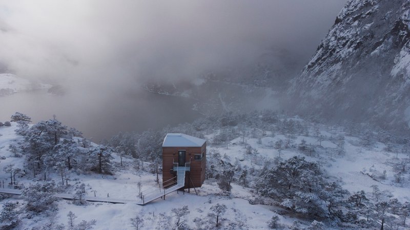 Aerial perspective of the timber structure in heavy snowfall with low cloud over the valley
