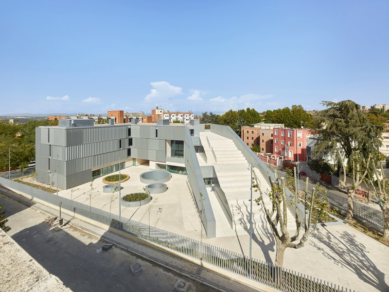 Elevated view of the triangular courtyard with circular planters and the metal-clad volumes surrounded by trees