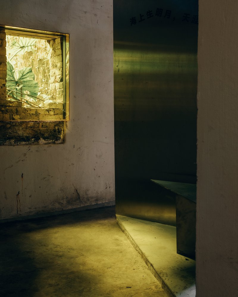 Polished brass doorway and window opening in a weathered plaster room with concrete floor