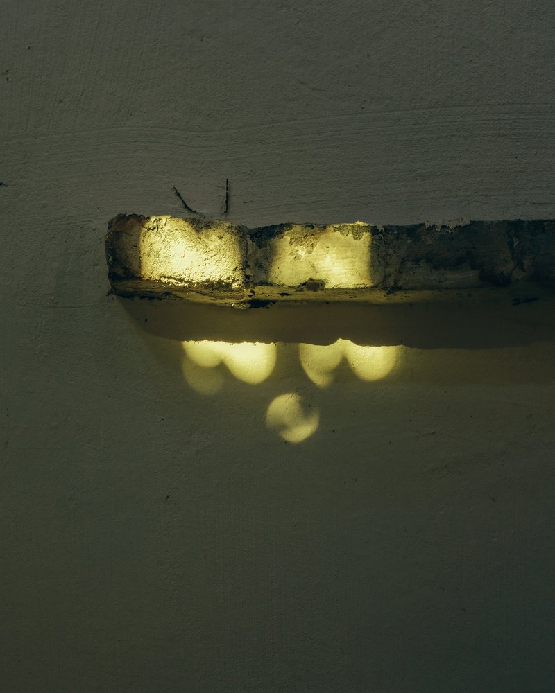 Illuminated brick ledge casting yellow light and shadow patterns on plaster wall