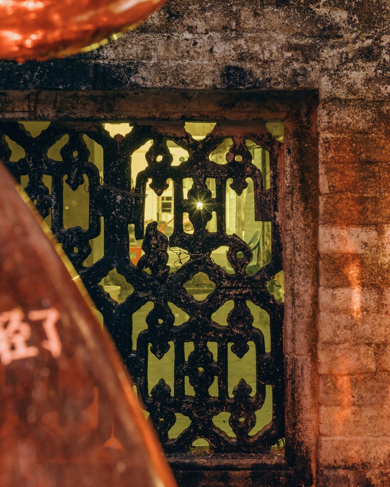Ornate cast iron grate set within weathered brick opening at dusk