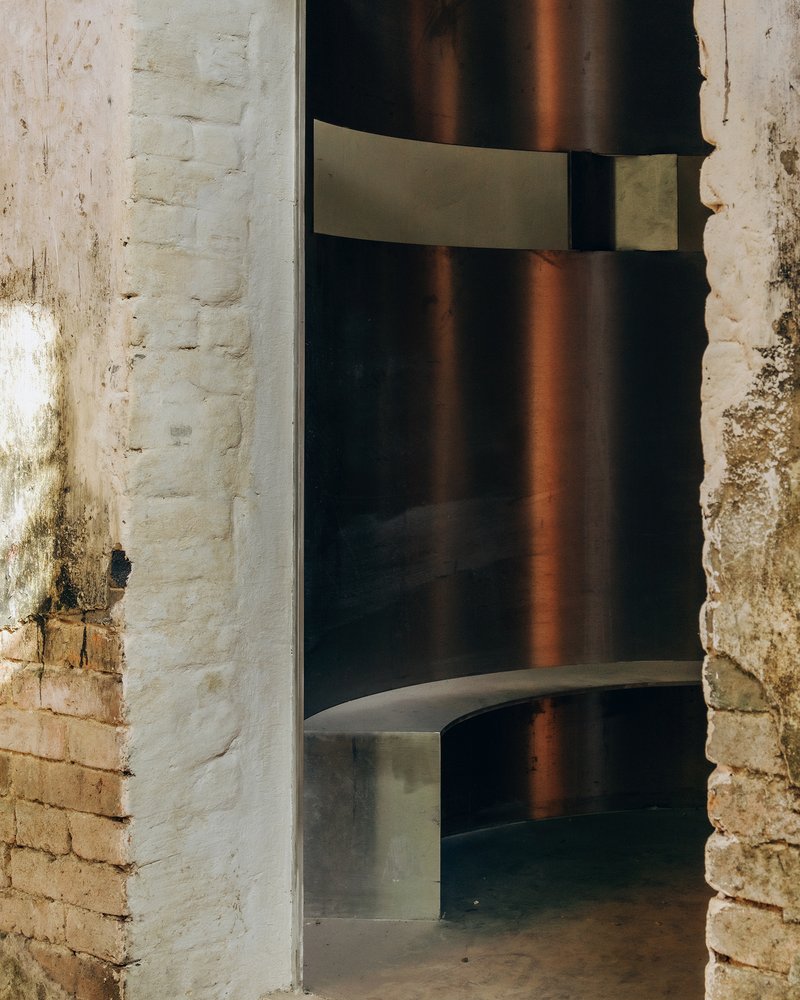 Doorway framed by aged white brick walls revealing a polished concrete interior with warm afternoon light