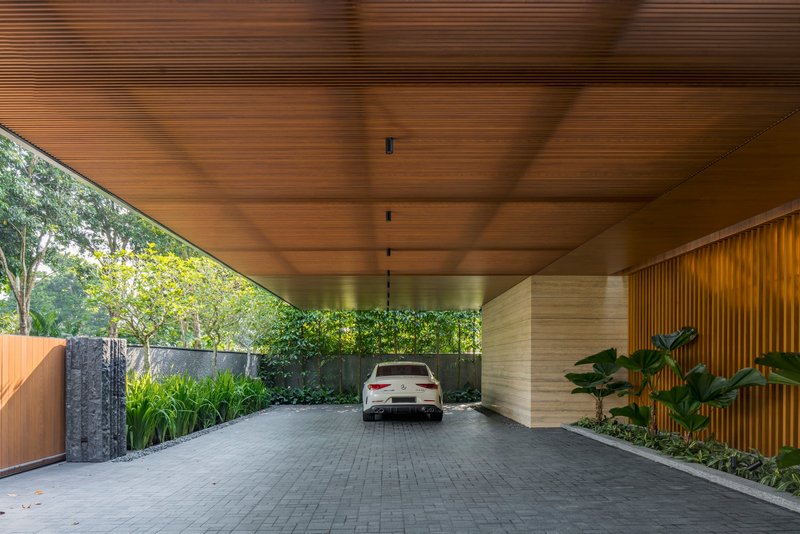 Covered carport with slatted timber ceiling and stone-clad columns framing a vehicle entrance