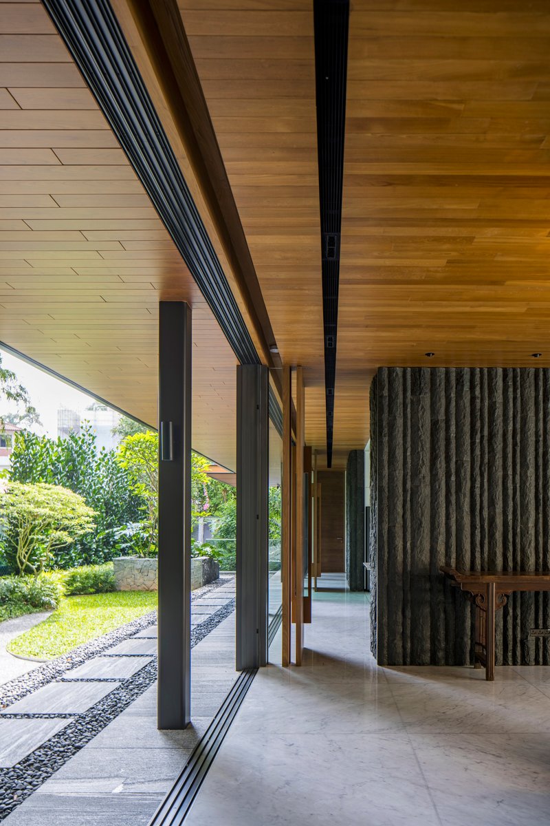 Covered walkway with timber-clad soffit and concrete flooring alongside a gravel garden path