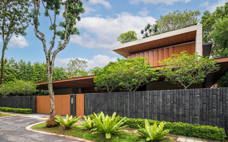 Street view of timber entry gate and textured concrete boundary wall with planted low hedges