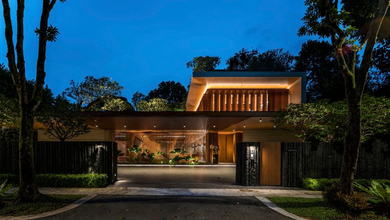 Front elevation with illuminated timber screens and carport at blue hour among surrounding trees