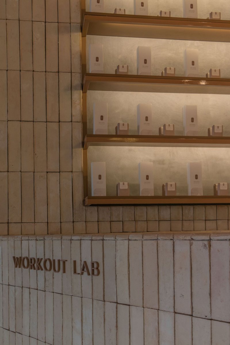 Tiled wall with integrated timber shelves displaying glass bottles under recessed lighting