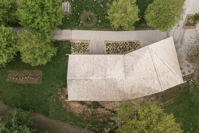 Aerial view of shingled roof with planted beds and pathways arranged around the pavilion structure